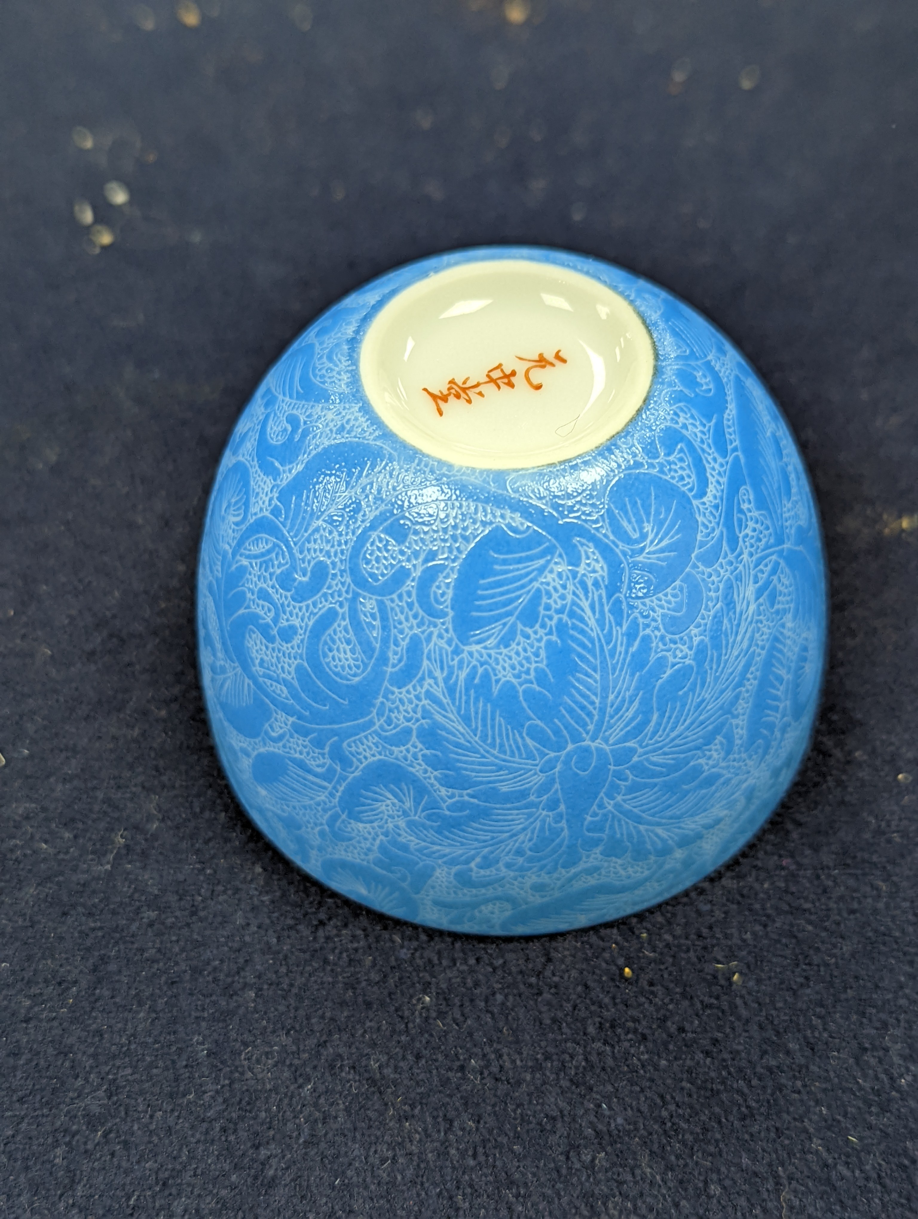A Japanese or Chinese sgrafitto blue enamelled cup, cased. 6cm diameter